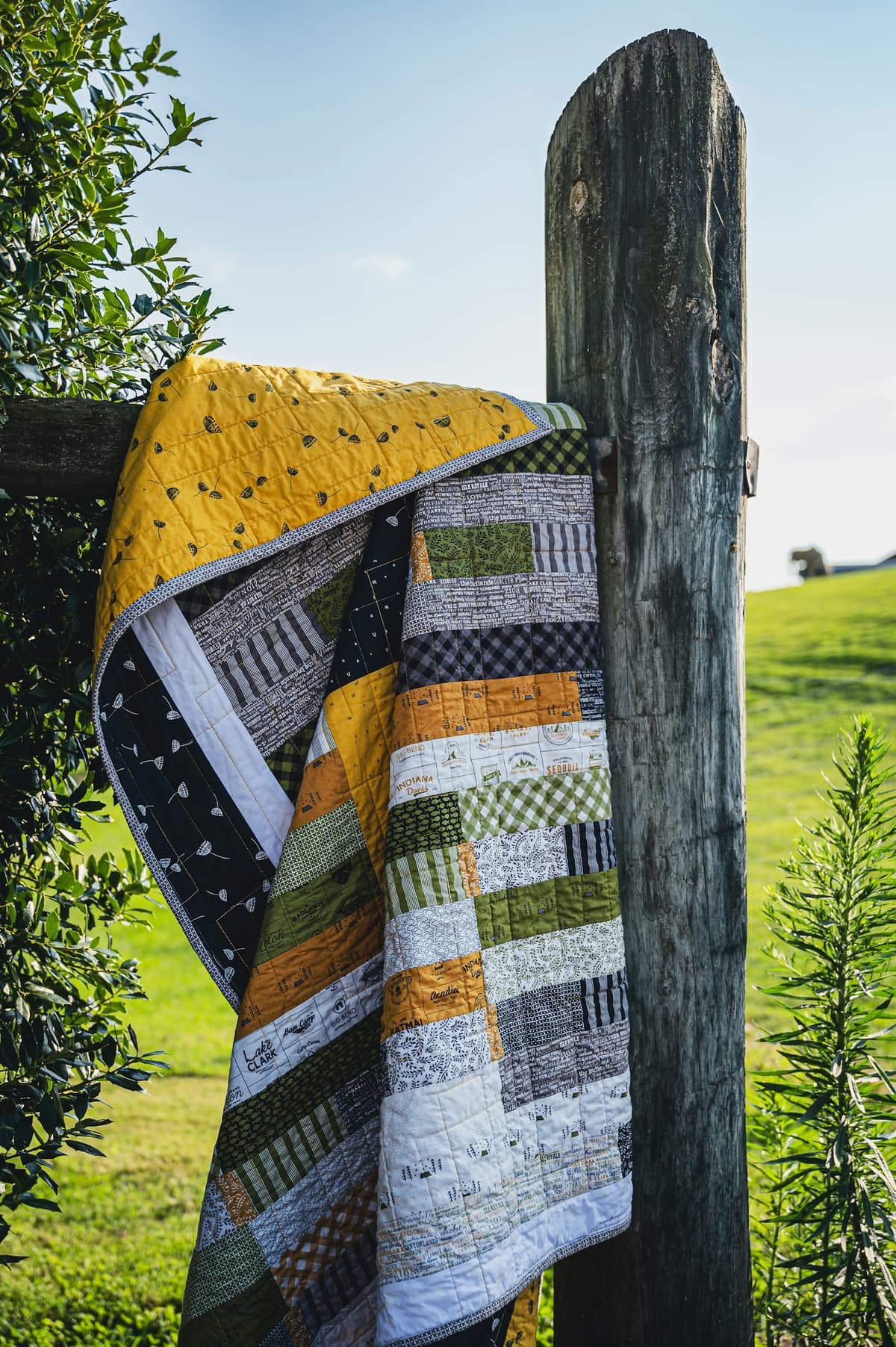 Rust and cream log cabin quilt draped over a wooden fence post
